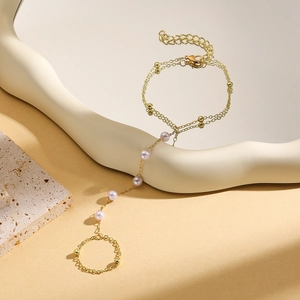 Detail of a gold finger bracelet with turquoise pearls and elegant layered chain design