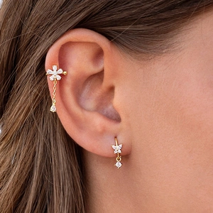Macro shot of gold butterfly stud and floral ear cuff with dangling chain and white zircon