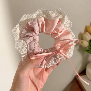 Detailopname van roze zijden scrunchie met kanten rand en strik vastgehouden