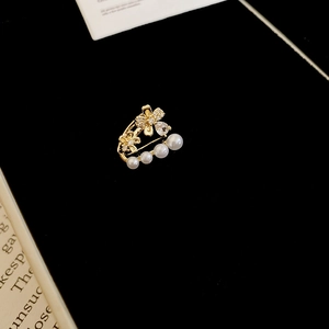 Détail de boucles d'oreilles fleurs dorées avec perles blanches et zircons sur fond noir