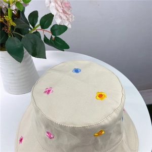 Close-up of colorful flower embroidery on a beige cotton sun hat with neat stitching