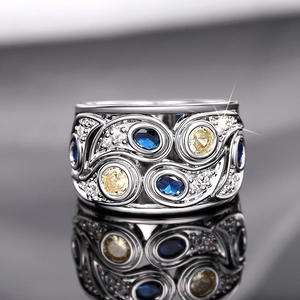 Macro d'une bague large argentée avec pierres bleues et gravure florale vintage