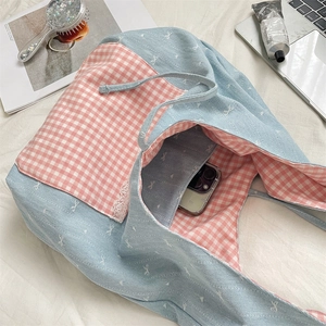 Macro view of blue bow-embroidered tote bag with pink plaid lining and lace trim detail