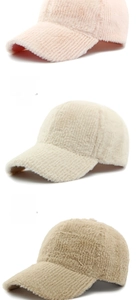 Close-up of plush winter baseball caps in pink, beige, and khaki showing soft fabric texture