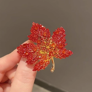 Close-up of maple leaf brooch with red crystal pavé and gold metallic vein details