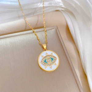 Detailed close-up of golden stainless steel necklace with blue evil eye pendant on fabric