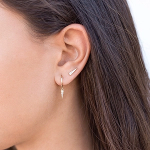 Close-up of golden geometric triangle earrings with rhinestones on a female model