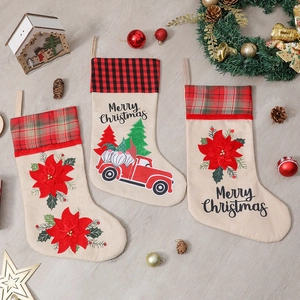Three festive Christmas stockings with red truck and dwarf patterns on wooden floor