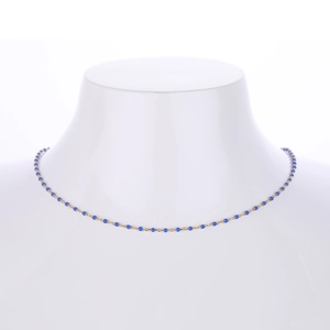Close-up of golden chain necklace with small blue beads on white mannequin neck