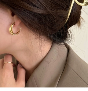 Gros plan de boucles d'oreilles clips dorées à boucles croisées sur un mannequin élégant