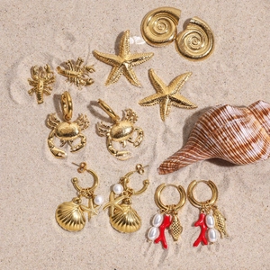 Gold ocean themed earring set with starfish and shells on a sandy beach background