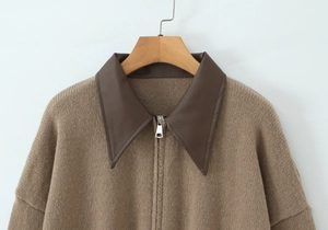 Detail of knit cardigan with brown faux leather collar and metallic zipper hardware