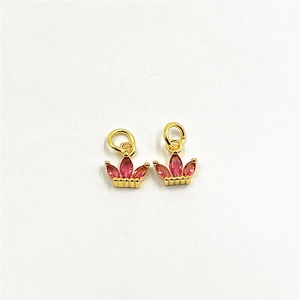 Close-up of gold crown pendant with pink zircon gems and polished metal finish