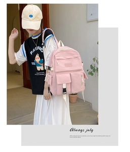 Pink multi-pocket student backpack with adjustable straps shown in a lifestyle street setting
