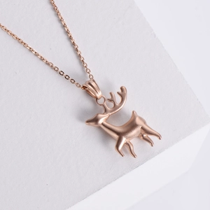 Elegant rose gold reindeer pendant necklace on a minimalist white geometric display stand