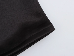 Detail of elegant black evening dress showing smooth fabric texture and precise stitching