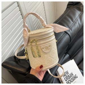 Detail view of cream barrel bag with embossed logo and decorative pink silk scarf handle