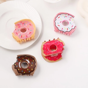Cute doughnut shaped hair claws in pink and chocolate colors on a white plate