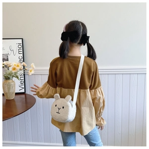 Rear view of child wearing a soft white plush bunny crossbody bag with long straps