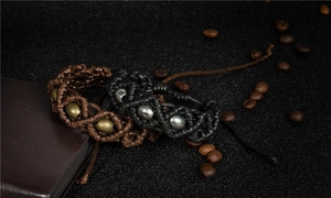 Close-up of handmade woven bracelets with adjustable cords on a textured dark background