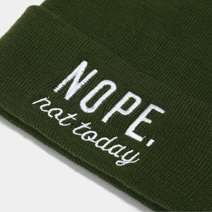 Deep green knit beanie featuring white NOPE. not today embroidery in a close-up angle