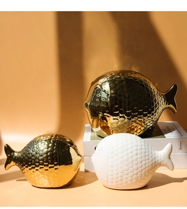 Vista macro de figuras de peces de cerámica texturizada en oro y blanco pulido