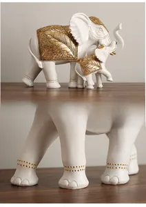 Detail view of white resin elephant statue with golden leaf texture on a wooden surface