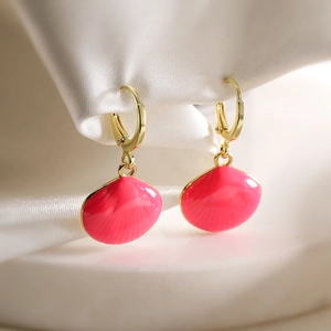 Macro detail of 18K gold-plated earrings featuring pink shell pendants on white silk