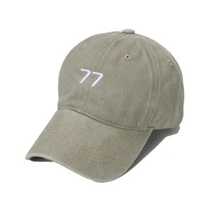 Detail of washed olive green baseball cap with white embroidered 77 on cotton fabric