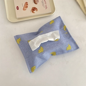 Close-up of blue fabric tissue holder with banana pattern and cotton linen texture