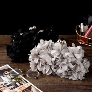 Detailed view of elegant floral evening clutches in black and silver on dark wooden table