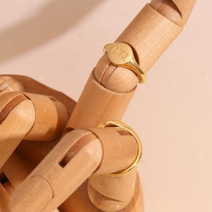 Detailed view of an 18K gold plated signet ring with LTJ engraving on a wooden model hand