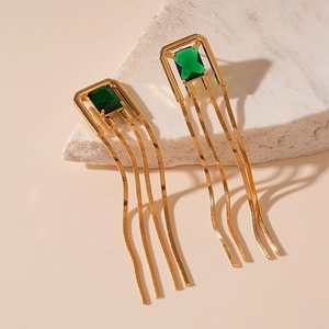 Detail of vintage gold tassel earrings with a rectangular emerald green gemstone