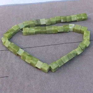 Close-up of green cube-shaped stone beads strung on a line for DIY jewelry making