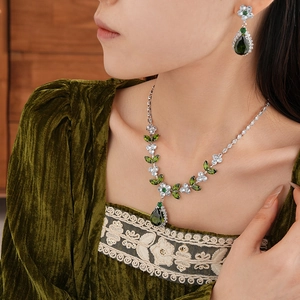 Detail of leaf flower necklace and earrings set with green teardrop gemstones