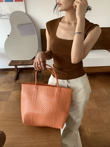 Detailed close-up showing the orange woven texture and sturdy handle of the summer tote bag