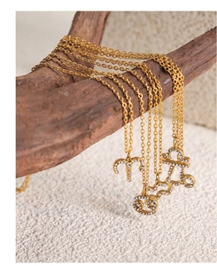 Detailed close-up of gold zodiac necklaces with sparkling white crystals on a wooden stand