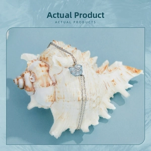 Dettaglio di un bracciale in argento s925 con ciondolo blu su una conchiglia bianca