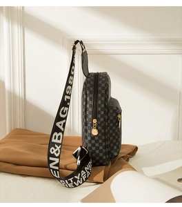 Detail view of dark grey cross-body chest bag with geometric grid pattern and wide logo strap