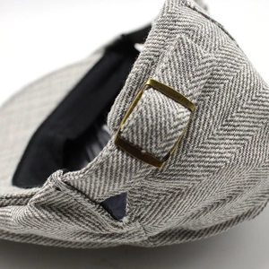 Detailed macro view of the grey herringbone fabric texture and bronze adjustable metal buckle