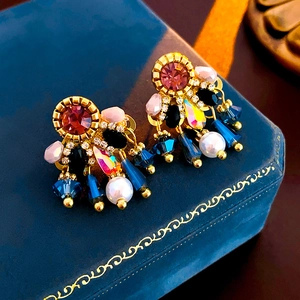Macro detail of vintage pearl tassel earrings with pink and blue crystals on blue velvet