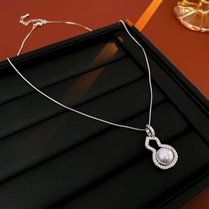 Close-up of a silver gourd-shaped pendant set with a white pearl and sparkling zircons