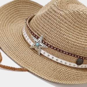 Detailed macro of a straw cowboy hat featuring silver star with turquoise stone inlay