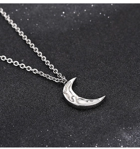 Macro shot of silver crescent moon necklace with textured surface and O-shaped chain
