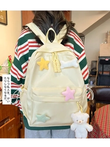 Detail of a cream yellow school backpack with colorful plush stars and a cute bear charm