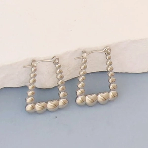 Detailed macro view of silver geometric hoop earrings with heart shaped bead accents
