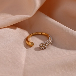 Detailed macro of golden drop-shaped ring with micro-set pearls on pink satin background