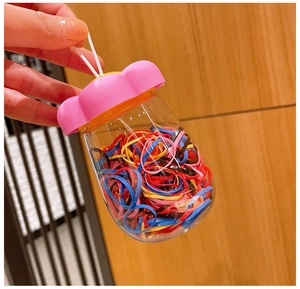 Portable bottle with assorted colorful hair elastics and floral lid with hand strap