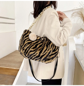 Detail of plush tiger print tote bag with gold chain strap and faux fur ball charm