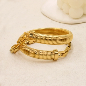 Golden snake-textured elastic bracelet with H-shaped buckle on stone background